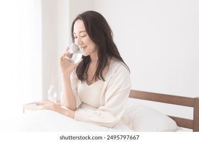 Woman drinking water in bed in the morning - Powered by Shutterstock