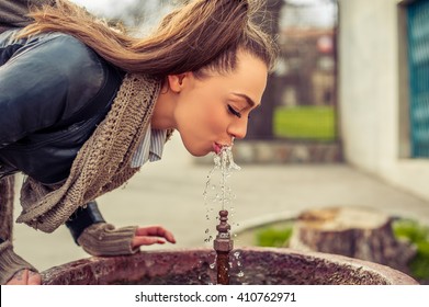 Woman Drinking Water From Fountain. Young Woman Drinking From A Fresh Water Drink Fountain