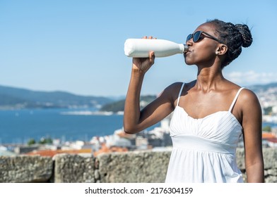 Woman drinking water on a hot day - Shutterstock ID 2176304159