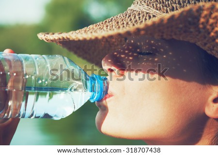 Woman drinking water in summer sunlight