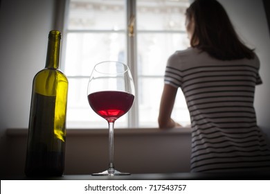 Woman Drinking Wine Alcohol Alone Looking Out Her Window.  Depression, Alcoholism, Lonely Person Concept.  