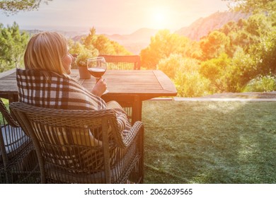 Woman Drinking Wine On The Terrace On A Sunny Fall Day. Girl Enjoys Nature And Fresh Air In A Plaid. Autumn Style.