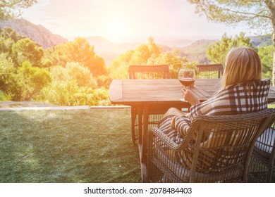 Woman Drinking Wine On The Terrace On A Sunny Fall Day. Girl Enjoys Nature And Fresh Air In A Plaid. Autumn Style.