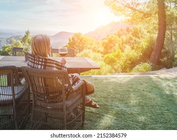 Woman Drinking Wine On The Terrace On A Sunny Spring Day. Girl Enjoys Nature And Fresh Air In A Plaid, Springtime Style.