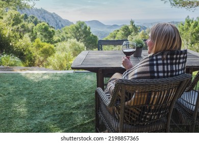 Woman Drinking Wine On The Terrace On A Sunny Fall Day. Girl Enjoys Nature And Fresh Air In A Plaid. Autumn Style.