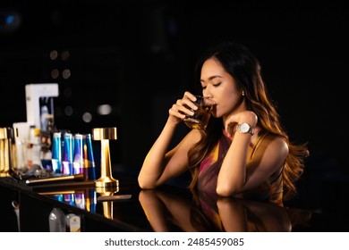 A woman drinks alcohol and gets drunk at a bar at night.. - Powered by Shutterstock