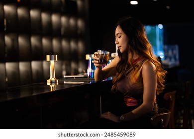 A woman drinks alcohol and gets drunk at a bar at night.. - Powered by Shutterstock