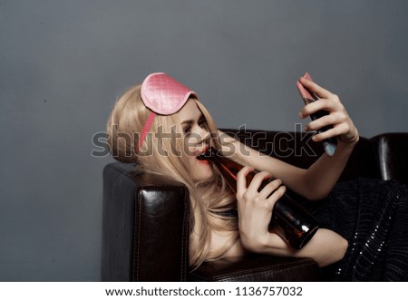  woman drinks from a bottle with a phone                              