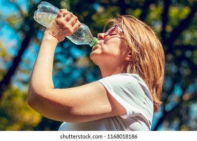 Woman Drinks Clean Water From A Bottle Outside In A Park