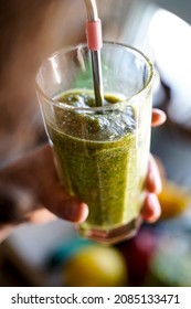 A Woman Drinks A Green Smoothie Fruit Shake Using A Metal Straw.