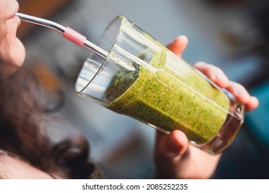 A Woman Drinks A Green Smoothie Fruit Shake Using A Metal Straw.