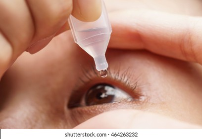 Woman dripping eye with eyes drops close up - Shutterstock ID 464263232