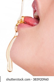 Woman dripping honey on her tongue