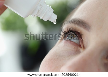 Woman dripping into her eyes with antibacterial drops closeup