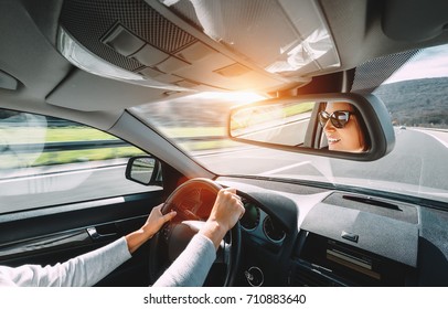 Woman drive a car reflects in back view mirror