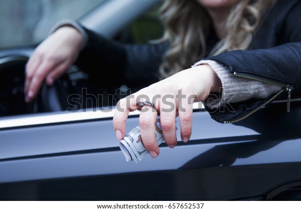 The woman driver of the car\
offering cash money. (corruption, fraud, money, finance\
concept)
