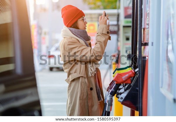 woman driver checking cost of gasoline, step
flowing up and down of cost of gasoline in market makes worry to
the cost of life of the people cosumption
