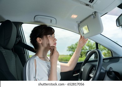 Woman Driver Checking Her Face By Sun Visor Mirror.