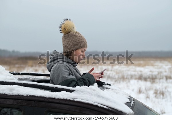 A woman driver got lost in\
a snow-covered field and looked out the hatch of a car to look\
around