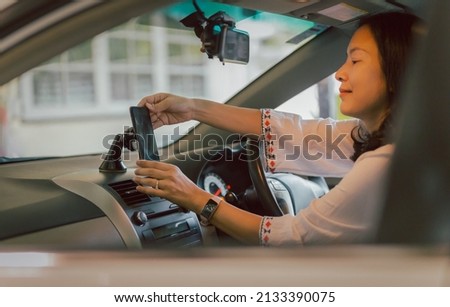 Woman driver hand adjust cell phone in stand holder for direction