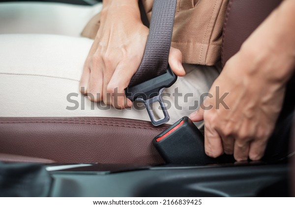 woman driver hand fastening seat belt during\
sitting inside a car and driving in the road. safety, trip, journey\
and transport concept
