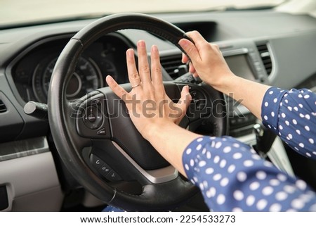 Woman driver hand honking her car horn to prevent accident. Driving safety concept