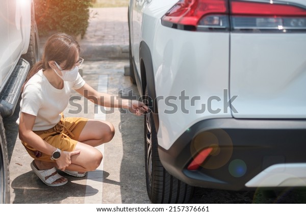 Woman driver hand inflating tires of vehicle,\
removing tire valve nitrogen cap for checking air pressure and\
filling air on car wheel at gas station. self service, maintenance\
and safety