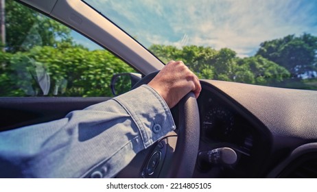 Woman Driver Hand On Car Steering Wheels While Driving Focus On Hand. Bumpy Rural Country Side Road. Travelling And Vacation Road Trip At Sunny Summer. Vehicle Driver Holding Car Steering Wheel.