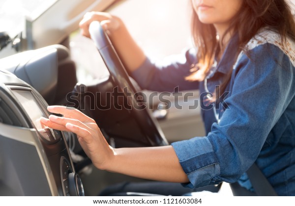 woman\
driver hand touching the screen entering an address into the\
navigation system and turning on car radio\
system.