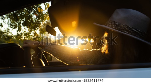 Woman\
driver with hat. Sunshine from the car\
window