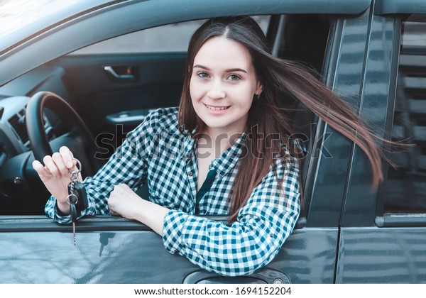 Woman\
driver holds car keys and smiles, female\
driver