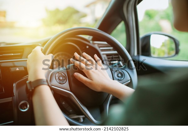 Woman Driver presses the horn of the car to attract\
the attention of the car bully and avoid road accident. pushing\
horn while driving sitting of a steering wheel press car, honking\
sound to warn othe