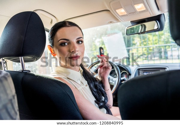 Woman driver\
showing car key inside\
automobile