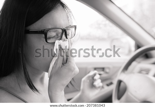 Woman\
driver sneezing in the car. Sick driver\
woman.