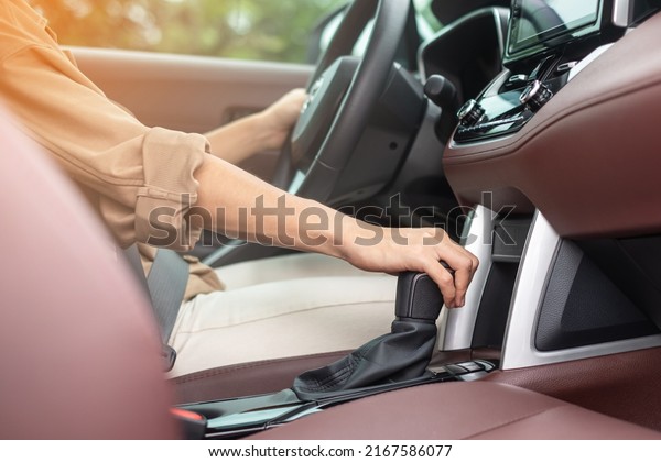 woman driver stick shift\
transmission a car gear, hand controlling steering wheel during\
vehicle moving. Journey, trip and safety Transportation\
concepts