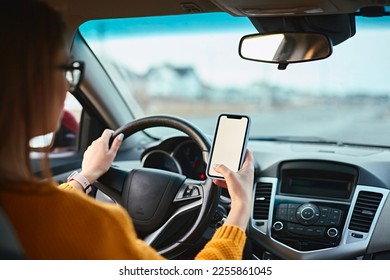 woman driver using mobile phone screen blank mockup on the road while driving a car - Powered by Shutterstock