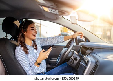 Woman Driver Using A Smart Phone In Car. Woman Driver Using A Smart Phone In Car. Leisure, Road Trip, Technology, Travel And People Concept - Happy Woman Driving Car With Smarhphone