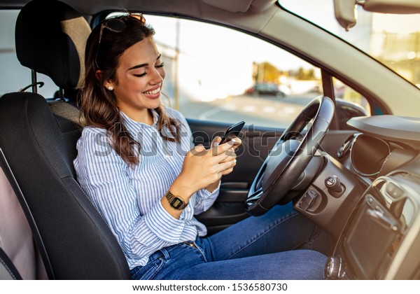 Woman driver\
using a smart phone in car. Woman driver using a smart phone in\
car. Leisure, road trip, technology, travel and people concept -\
Happy woman driving car with\
smarhphone