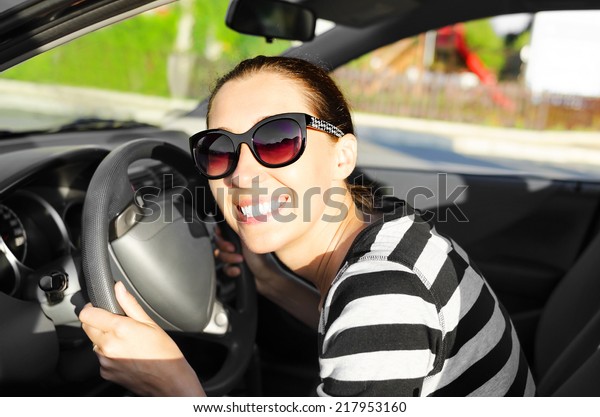 Woman drives a car\
on the road and smiling