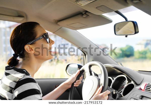 Woman drives a car\
on the road and smiling