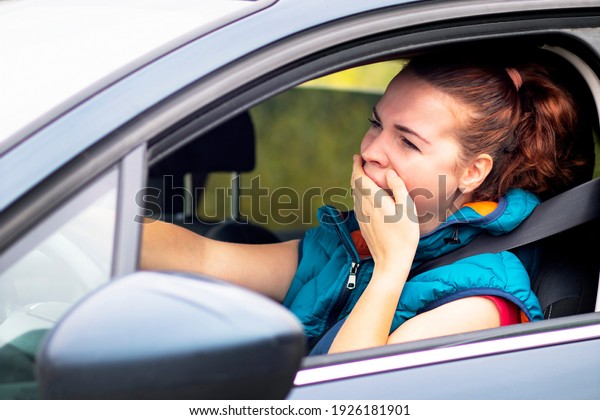 A woman drives a car, a woman in a traffic jam\
in sunglasses, yawns covering her mouth. Fall asleep while driving\
an automobile
