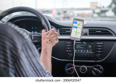 A woman drives a car using the navigator in a mobile iphone, yandex maps - Moscow, Russia, June 27, 2021