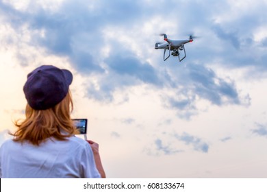 Woman drives a drone towards the cloudy sky