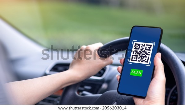 the woman driving a black car\
Using a smartphone to scan and pay bills. in the mobile\
application.