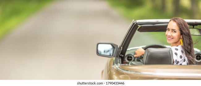 Woman Driving In A Cabriolet Looks Back And Smiles Into The Camera. 