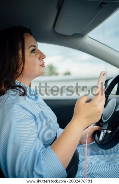 The woman driving the car drives the car and texts\
on the phone. selective focus. dealing with business issues on the\
road.