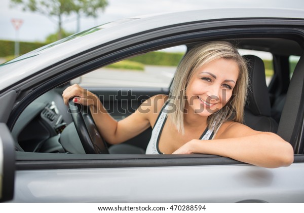 Woman driving a car - female driver at a wheel of\
a modern car, looking happy, smiling with a relaxed smile (shallow\
DOF; color toned image)