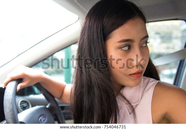 Woman driving car. Female fresh driver at car wheel\
steering gear, looking back, check behind going reverse. young\
Asian girl new driver parking car, ride car backward. drive reverse\
turning back.