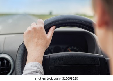 Woman Driving Car, Hand On Steering Wheel, Looking At The Road Ahead, Road Safety, Selective Focus On Hand With Shallow Depth Of Field.