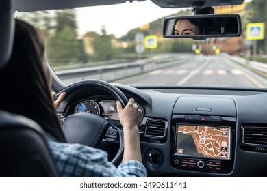 Woman driving a car, hands on the wheel close-up, view from the back to the road.